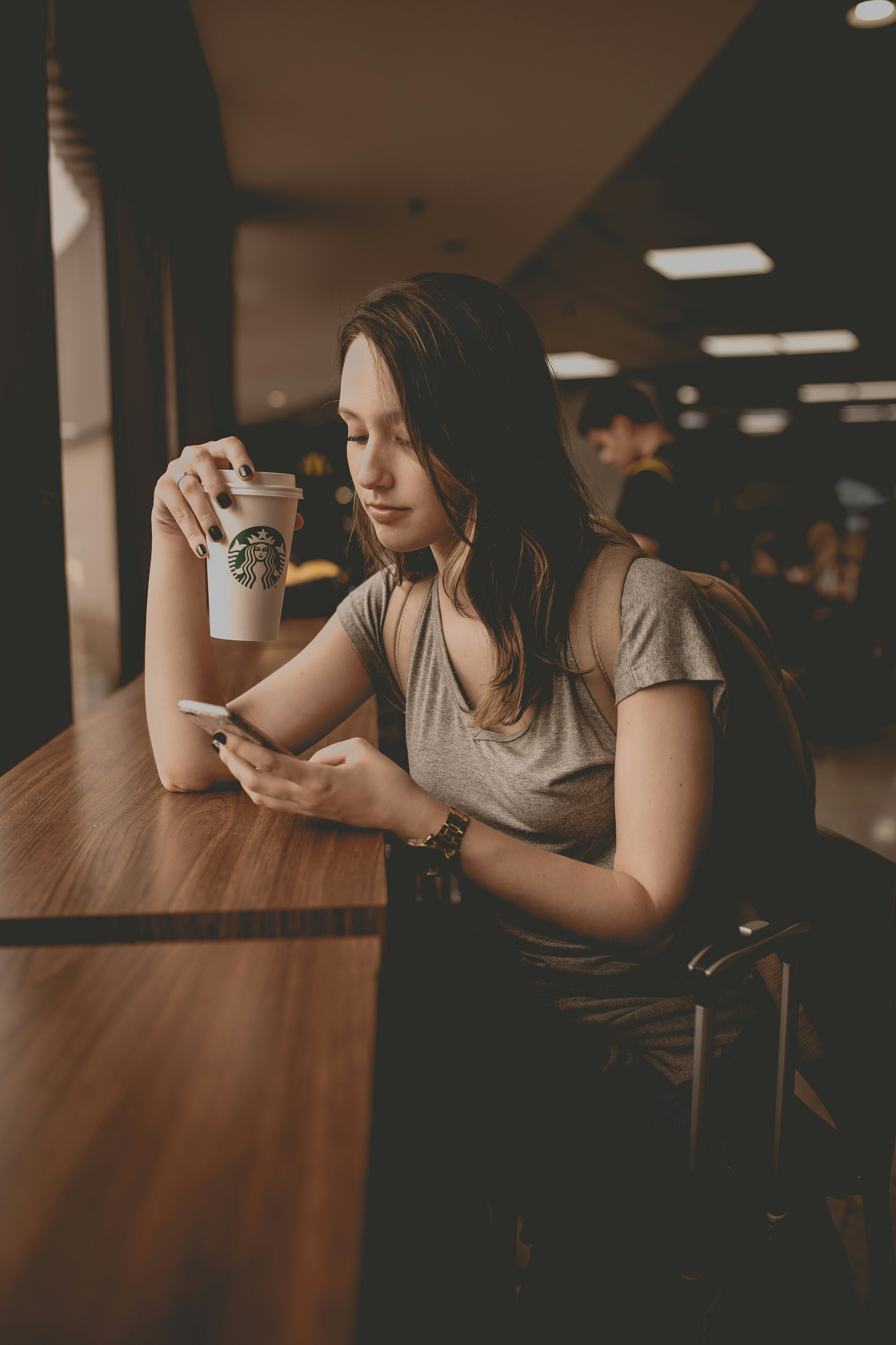 woman holding starbucks disposable cup and smartphone